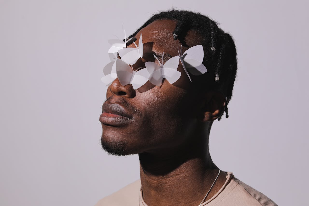 Artistic portrait of a man with paper butterflies covering his eyes, symbolizing imagination.